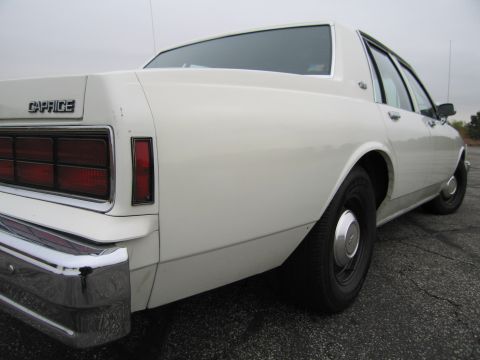 1991 Ford LTD Crown Victoria - White Chevrolet Caprice sedan seen from the rear quarter angle, showing its distinctive taillights and chrome bumper.