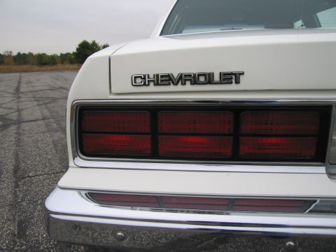 1991 Ford LTD Crown Victoria - The rear of a white Chevrolet sedan is visible, its distinctive taillight design and badging.