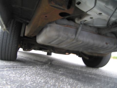 1991 Ford LTD Crown Victoria - The undercarriage of a vehicle is visible, including the fuel tank and suspension components.