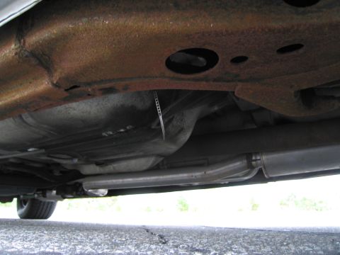 1991 Ford LTD Crown Victoria - The undercarriage of a vehicle displays significant rust on the frame and a visible exhaust system.