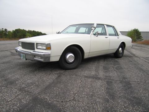 1991 Ford LTD Crown Victoria - This white sedan has a distinctive grille and body style, suggesting an older model year.