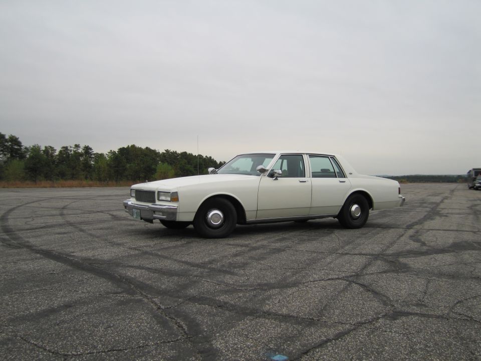 White 1990 Chevrolet Caprice sedan parked on asphalt with tire marks