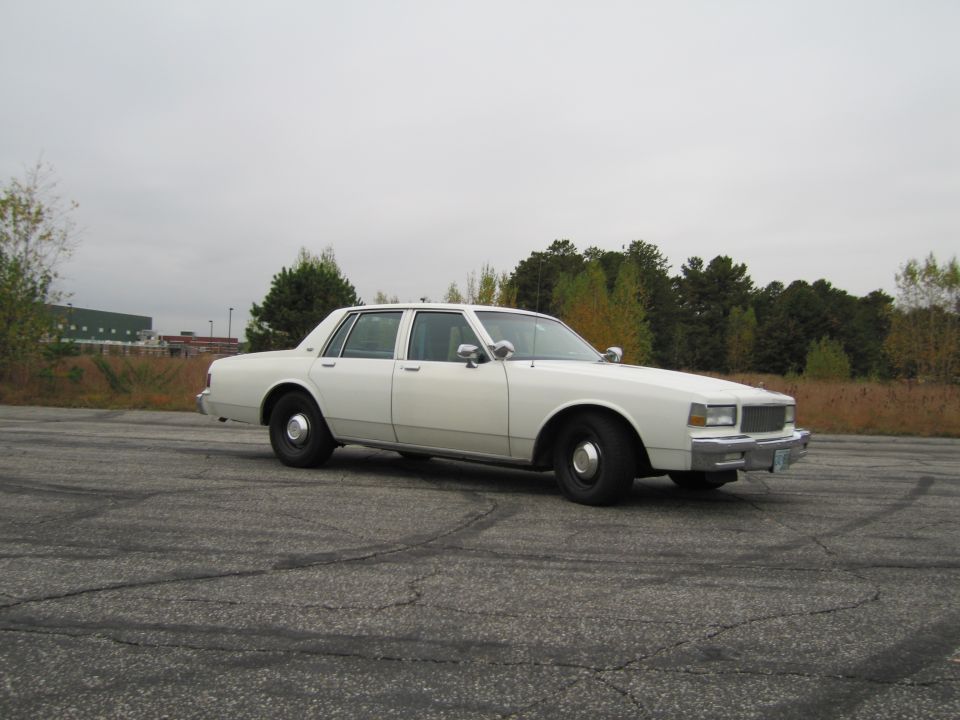 White 1980s Chevrolet Caprice sedan parked on cracked asphalt