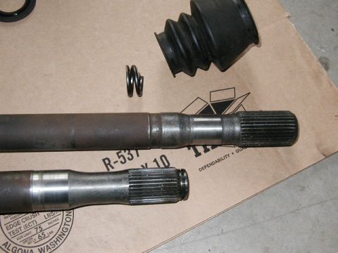 1995 Ford Bronco - Two axle shafts, a CV boot, and springs are laid out on a cardboard surface with visible text.