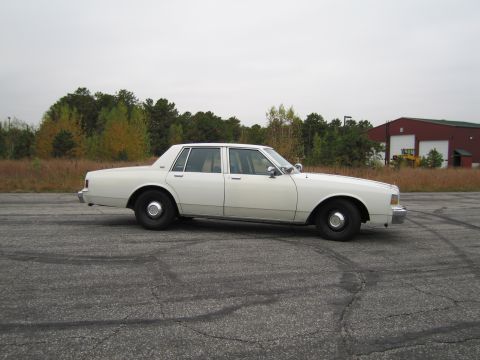 1991 Ford LTD Crown Victoria - A white sedan is parked on a lot with tire marks visible on the asphalt.