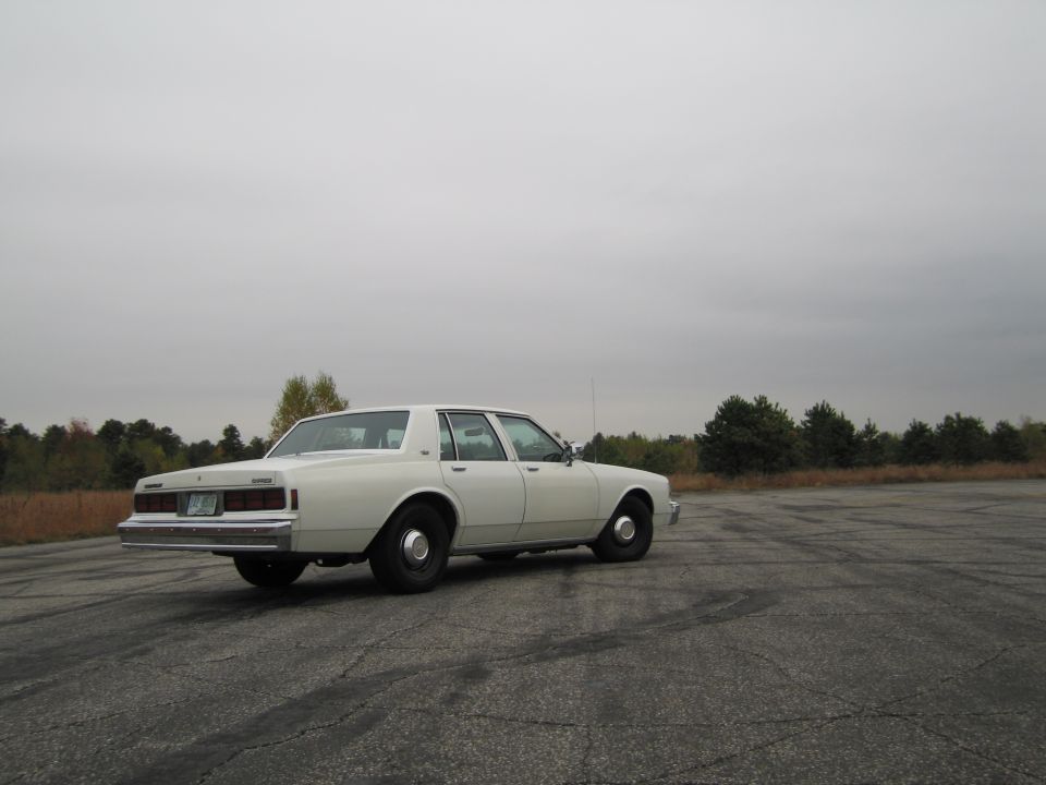 White sedan from rear quarter, parked on asphalt