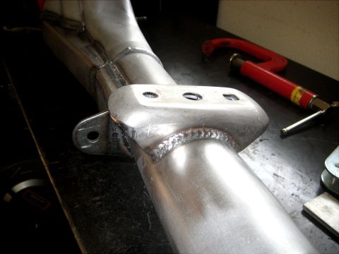 1996 Ford Bronco - A metal component with visible welds and a mounting bracket is shown on a workbench.