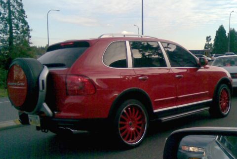 1969 Lincoln Continental - This red SUV, equipped with an external spare tire and custom wheels, is seen from the rear in traffic.