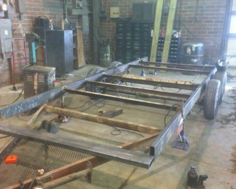 1900 Ford C-350 (Centurion Conversions) - Unfinished trailer frame rests on jack stands in a workshop setting, awaiting further construction.