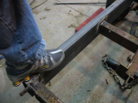 1900 Ford C-350 (Centurion Conversions) - A person's foot is placed on a metal frame, possibly during construction or repair.