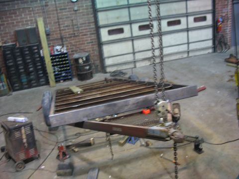 1900 Ford C-350 (Centurion Conversions) - Workshop scene showing a trailer frame under repair, with chains and equipment around.