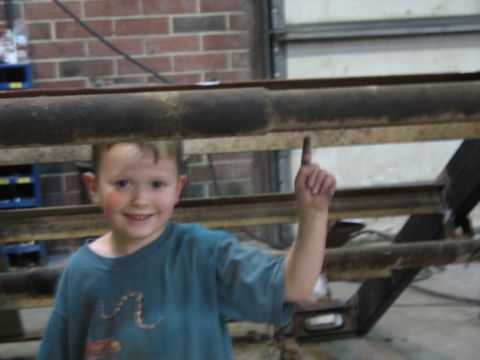 1900 Ford C-350 (Centurion Conversions) - Young boy points to industrial metal beams in a workshop setting.