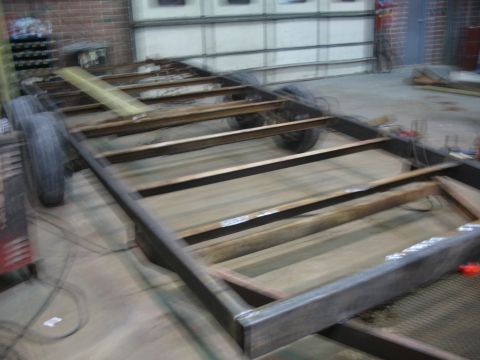 1900 Ford C-350 (Centurion Conversions) - The bare metal frame of a trailer sits on the floor of a workshop, awaiting construction.