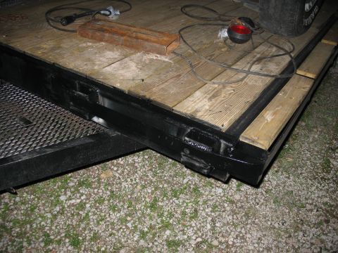 1900 Ford C-350 (Centurion Conversions) - A close-up view of a trailer deck shows wooden planks, a black metal frame, and an electrical cord lying on the surface.
