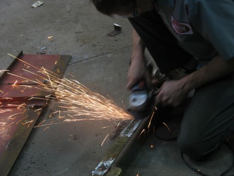 1900 Ford C-350 (Centurion Conversions) - Grinding metal with an angle grinder, producing sparks. No vehicle visible.