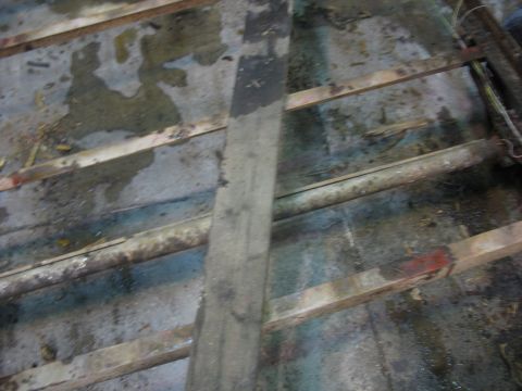 1900 Ford C-350 (Centurion Conversions) - A scene of a wet concrete floor with wooden planks, possibly a workshop or storage area.