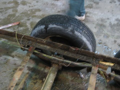 1900 Ford C-350 (Centurion Conversions) - Close-up view of a trailer chassis and tire, showing the frame and wiring.