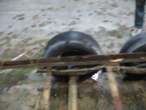 1900 Ford C-350 (Centurion Conversions) - A blurry view of trailer tires and frame, with a person standing nearby on a wet surface.