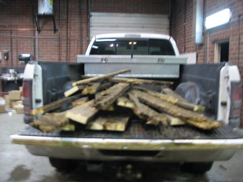 1900 Ford C-350 (Centurion Conversions) - A white pickup truck's bed is filled with lumber and a metal toolbox, seen from behind.