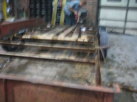 1900 Ford C-350 (Centurion Conversions) - A person works on a trailer with wooden planks, showing a scene of repair or construction.