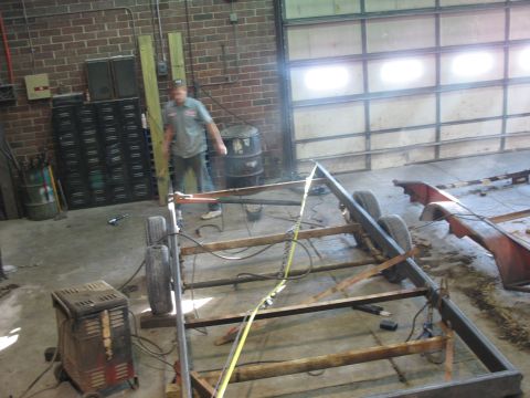 1900 Ford C-350 (Centurion Conversions) - A man is welding a metal frame for a trailer in a workshop setting.