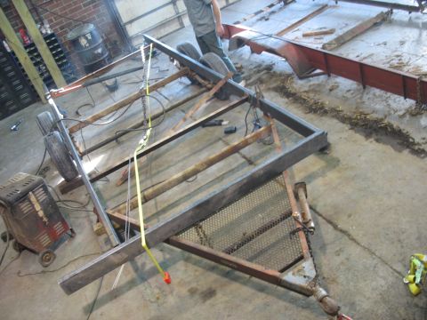 1900 Ford C-350 (Centurion Conversions) - A partially constructed trailer frame sits in a workshop, awaiting further assembly.