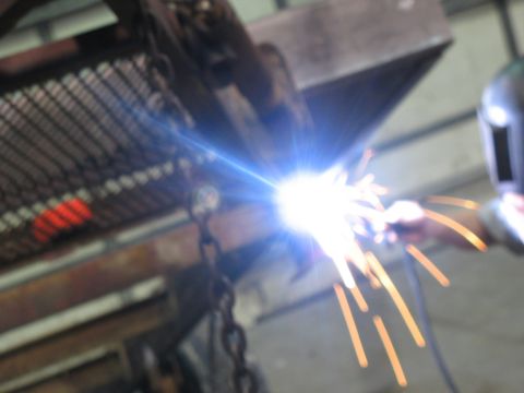1900 Ford C-350 (Centurion Conversions) - Welding sparks illuminate a workshop scene, with a welder wearing a mask.