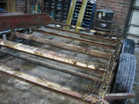 1900 Ford C-350 (Centurion Conversions) - A trailer chassis with wooden planks and two tires is shown in a workshop setting.