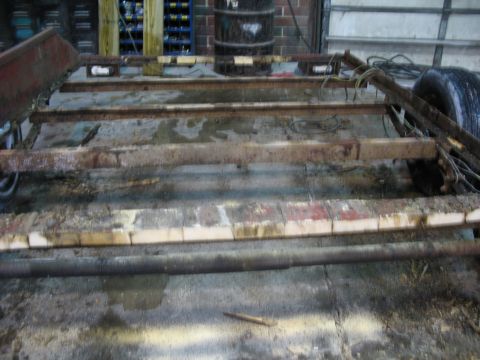 1900 Ford C-350 (Centurion Conversions) - Close-up of a weathered trailer frame, showing its structural components and a single tire.