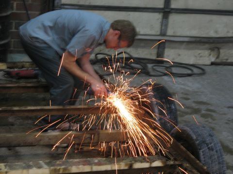 1900 Ford C-350 (Centurion Conversions) - A person is using an angle grinder on some metal, creating a shower of sparks.