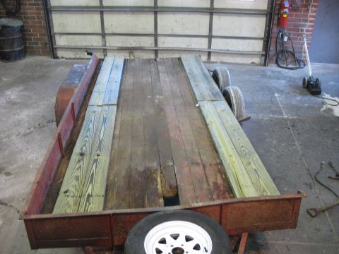 1900 Ford C-350 (Centurion Conversions) - A utility trailer with a wooden deck, showing signs of wear and repair, parked indoors.