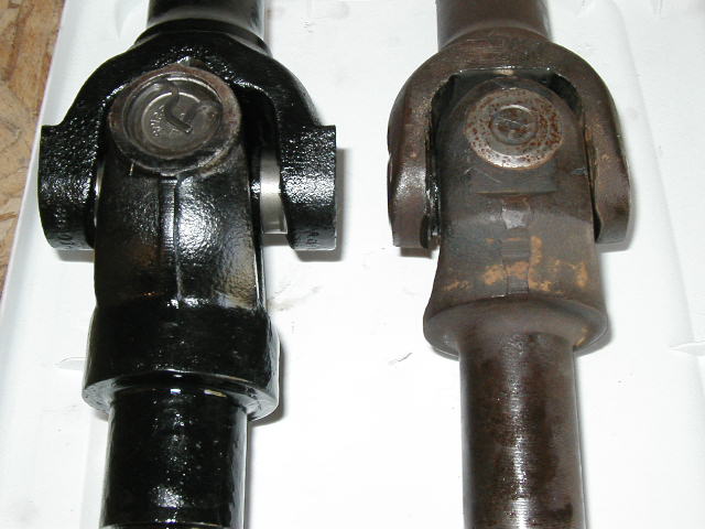 Two driveshaft U-joint yokes, one painted black, one rusty