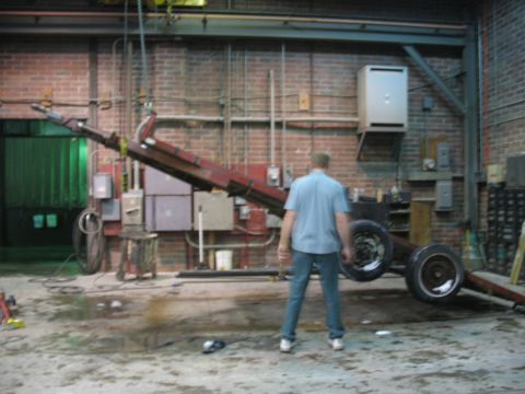 1900 Ford C-350 (Centurion Conversions) - A person stands near a red tow truck bed with dual wheels in a workshop.