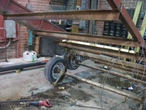 1900 Ford C-350 (Centurion Conversions) - Trailer frame and wheels in a workshop setting, with tools on the floor.