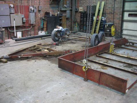 1900 Ford C-350 (Centurion Conversions) - Workshop scene with two trailer frames and a child on a tire.