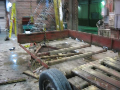 1900 Ford C-350 (Centurion Conversions) - The interior of a workshop shows a trailer frame undergoing repairs or construction.
