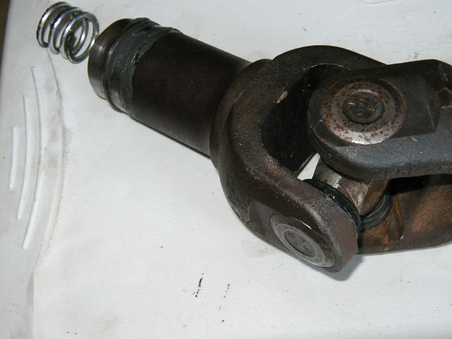 U-joint yoke with splined shaft and coil spring on white surface