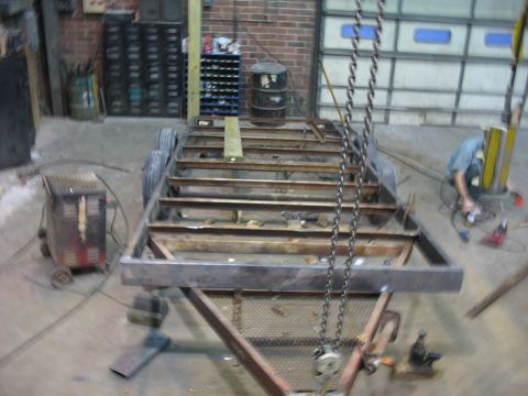 1900 Ford C-350 (Centurion Conversions) - A trailer frame is under construction in a workshop, with tools and equipment visible.