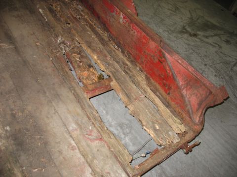 1900 Ford C-350 (Centurion Conversions) - Close-up view of a rusted metal frame with decaying wooden planks, showing signs of wear and tear.