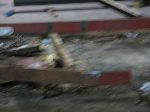 1900 Ford C-350 (Centurion Conversions) - The image shows a cluttered ground area with various pieces of debris and construction materials scattered around.
