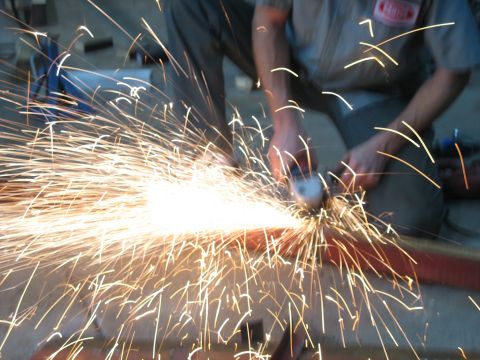 1900 Ford C-350 (Centurion Conversions) - A person uses an angle grinder on metal, producing a bright spray of sparks.