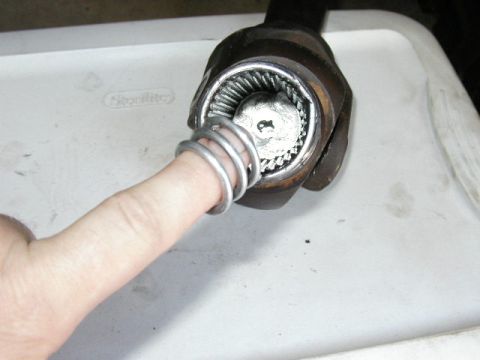 1995 Ford Bronco - U-joint with a finger and spring, likely a part from a vehicle.