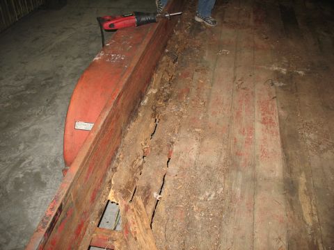 1900 Ford C-350 (Centurion Conversions) - A reciprocating saw is positioned on a damaged wooden trailer bed, indicating repair work is underway.
