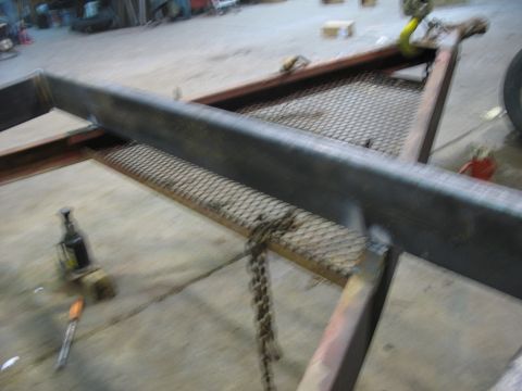 1900 Ford C-350 (Centurion Conversions) - A trailer frame is shown in a workshop setting with various tools and equipment.