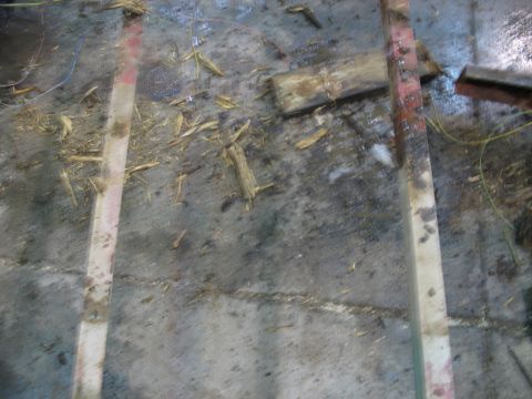 1900 Ford C-350 (Centurion Conversions) - The image shows a floor covered in debris, wood fragments, and water, with no visible vehicle parts.