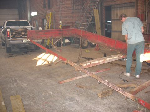 1900 Ford C-350 (Centurion Conversions) - A white pickup truck is connected to a red metal ramp structure inside a garage.