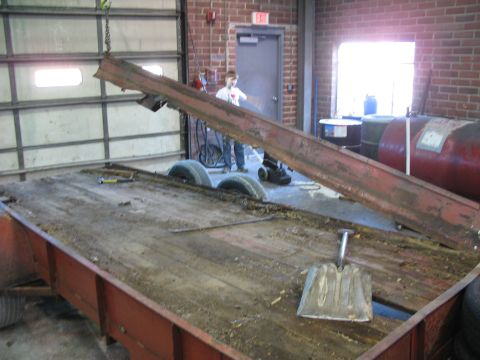 1900 Ford C-350 (Centurion Conversions) - A trailer is being worked on inside a garage with a person and equipment in the background.
