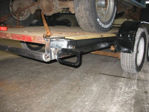 1900 Ford C-350 (Centurion Conversions) - Close-up view of a trailer hitch and rear axle, with chains used to secure a vehicle.