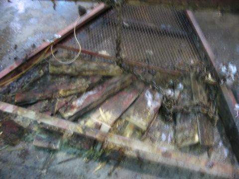 1900 Ford C-350 (Centurion Conversions) - A cluttered scene with debris and metal grating, showing no identifiable vehicle.