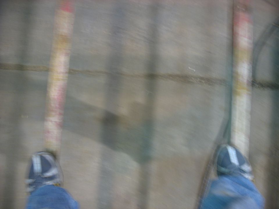 Feet in sneakers and jeans standing on a concrete surface with vertical lines